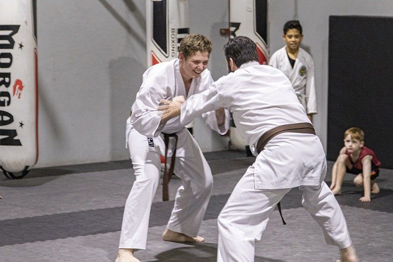 A group of people are practicing martial arts in a gym sponsored by morgan