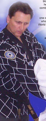 A man wearing a black karate uniform is holding a black belt