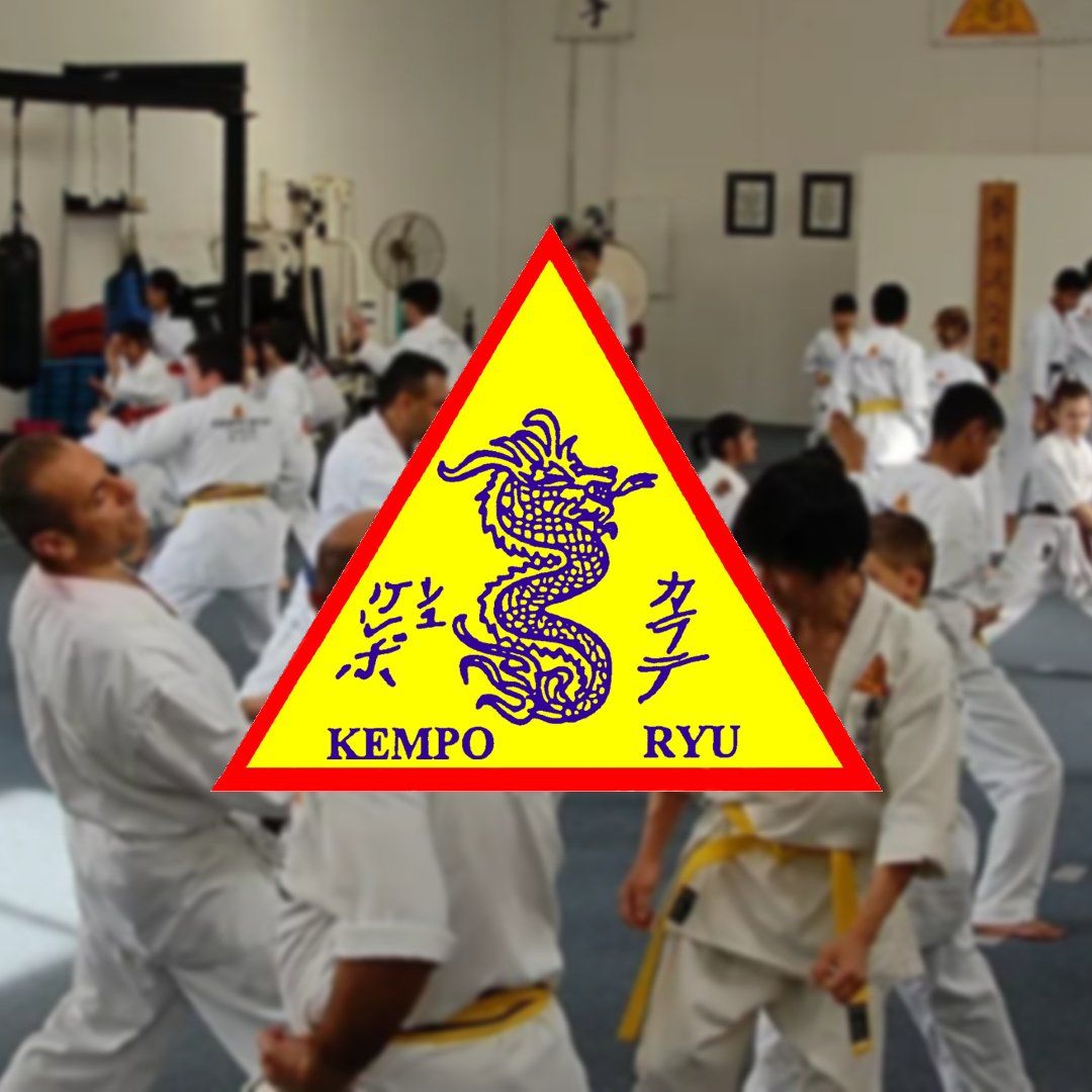 A group of people are practicing martial arts in a gym with a sign that says kempo ryu