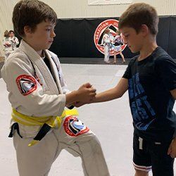 Two young boys are shaking hands in a gym.