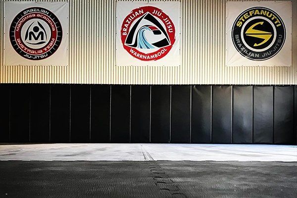 An empty gym with three logos on the wall including one for stefanutti