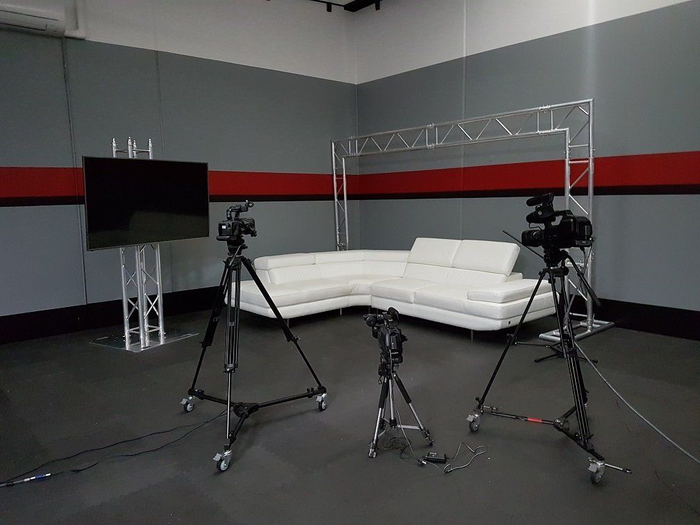 A room with a couch and two cameras on tripods.