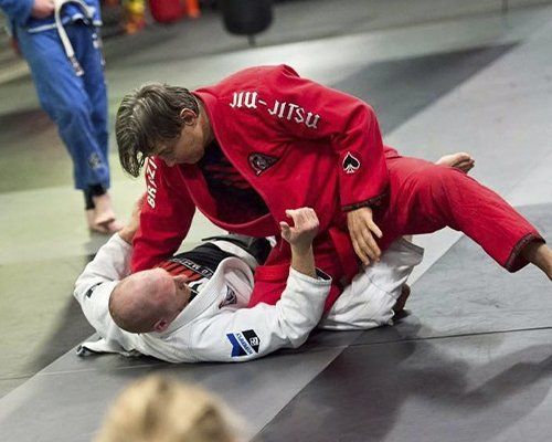 Two men are wrestling on a mat in a gym.