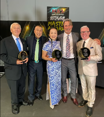 A group of men and women are posing for a picture holding awards