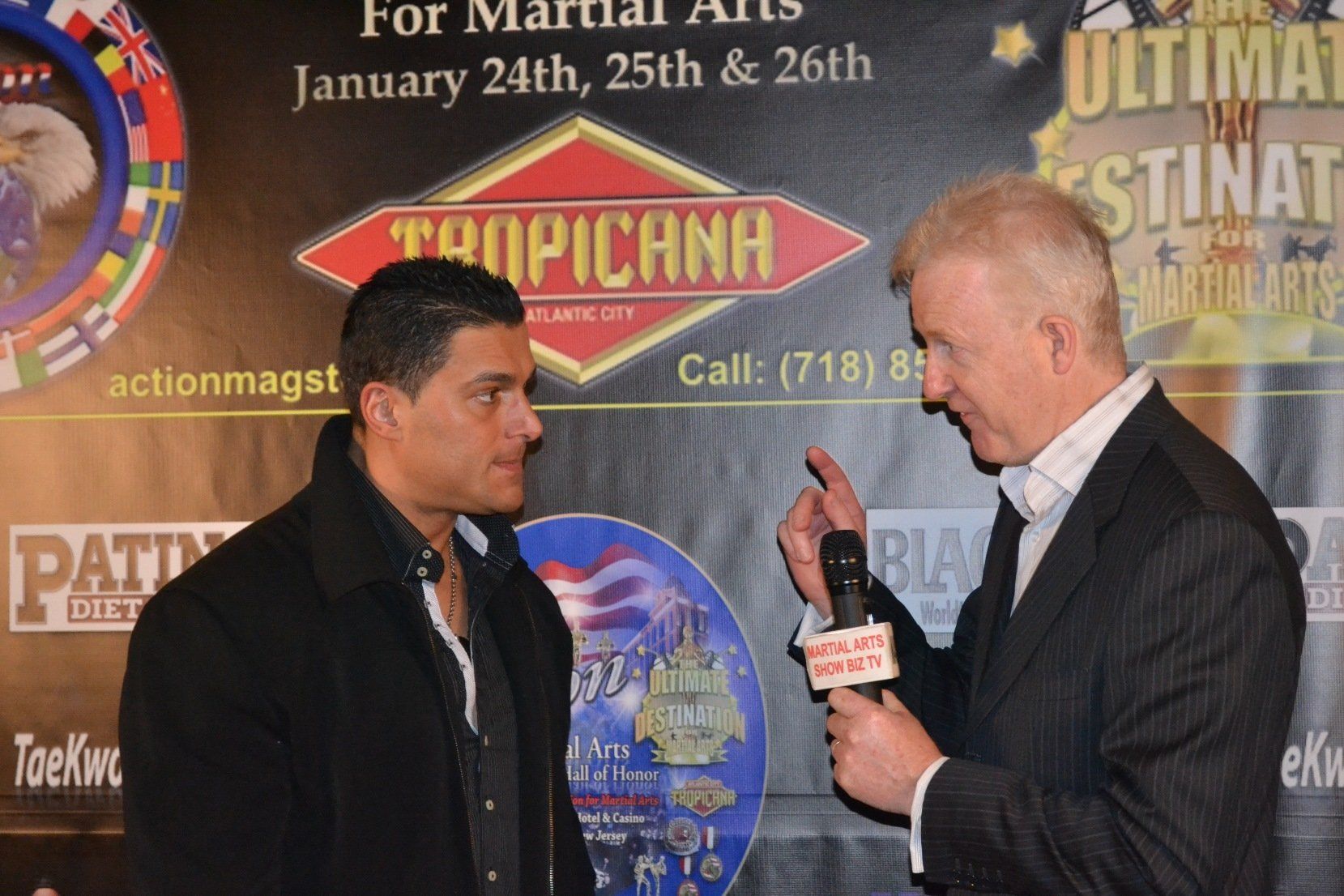 Two men are talking in front of a sign that says tropicana