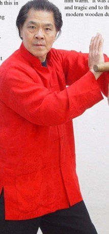 A man in a red jacket is holding a wooden stick