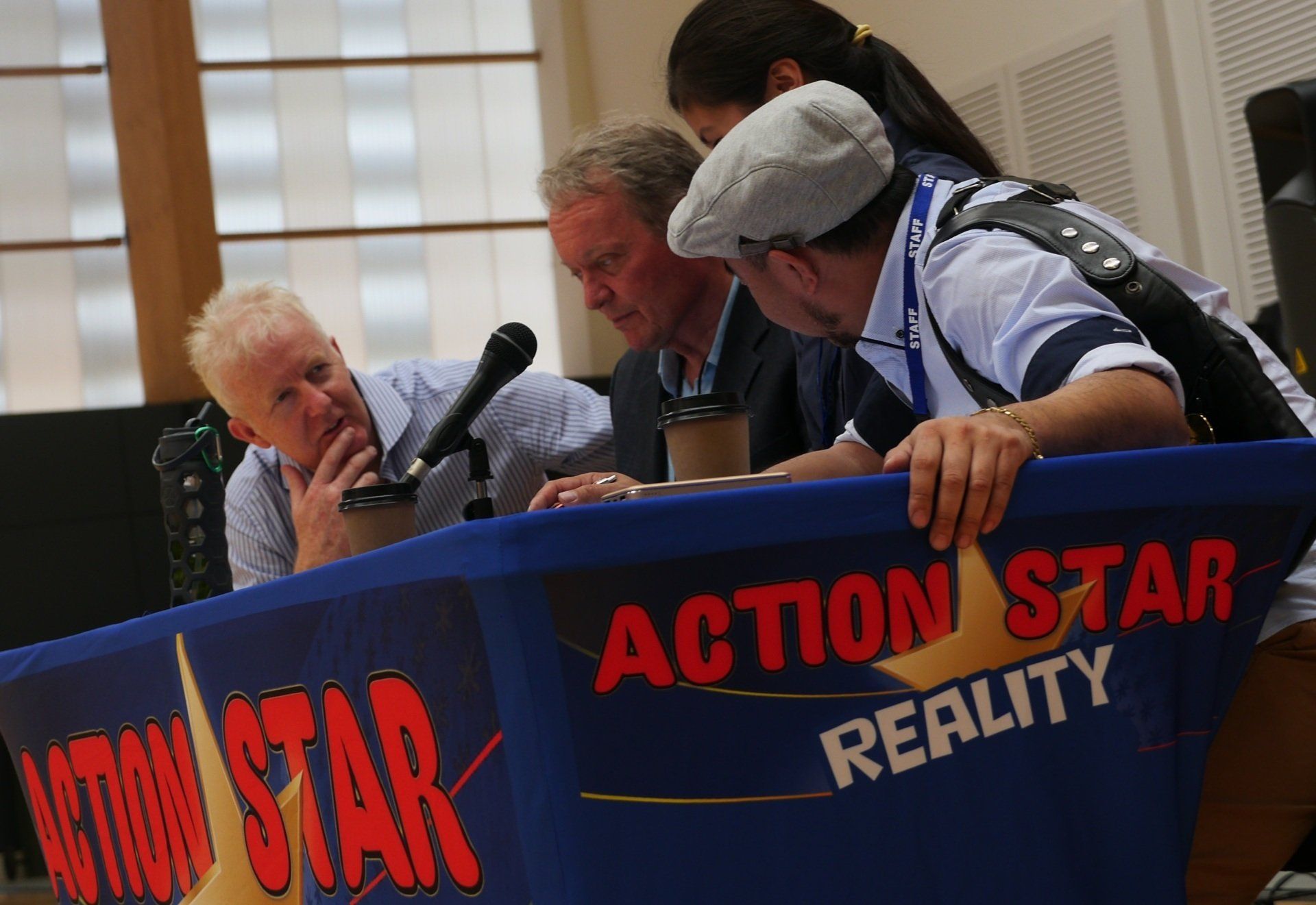 A group of people sitting around a table that says action star reality