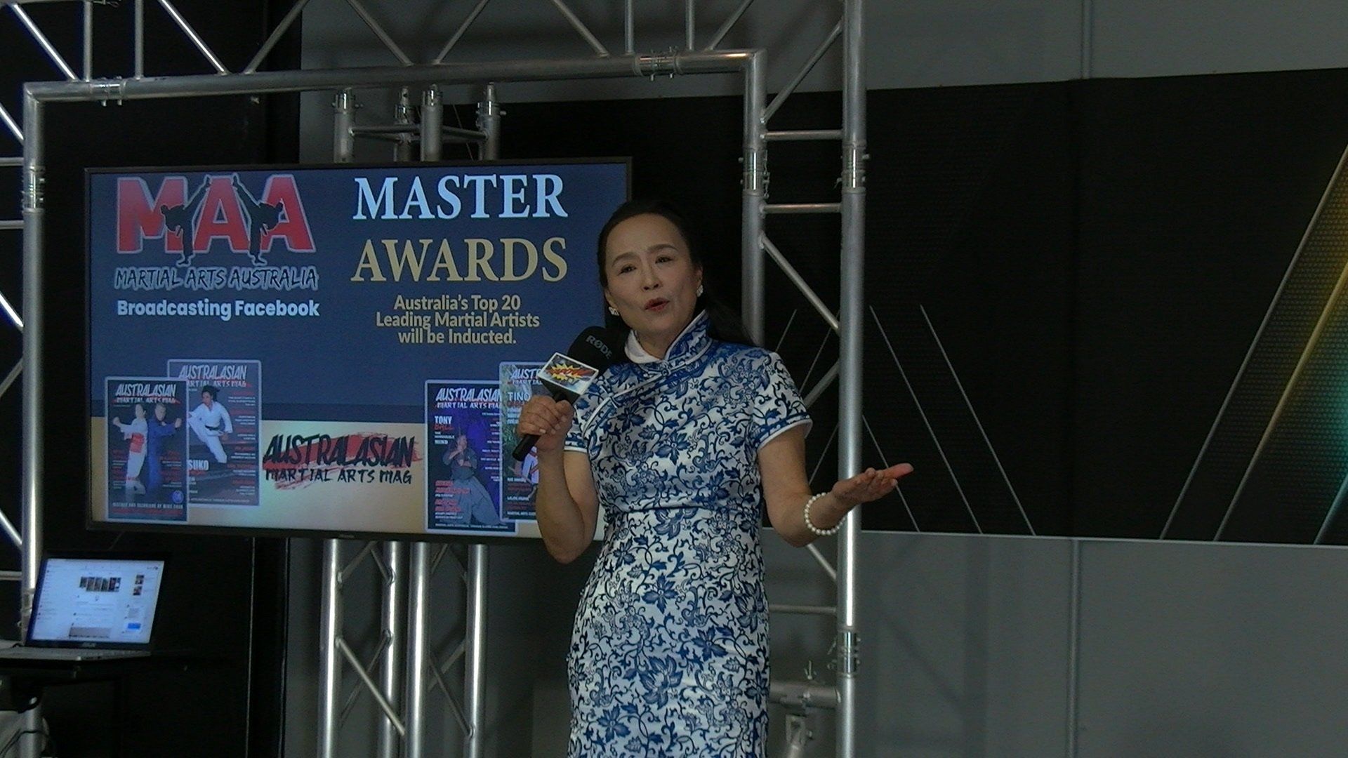 A woman is standing in front of a screen that says master awards