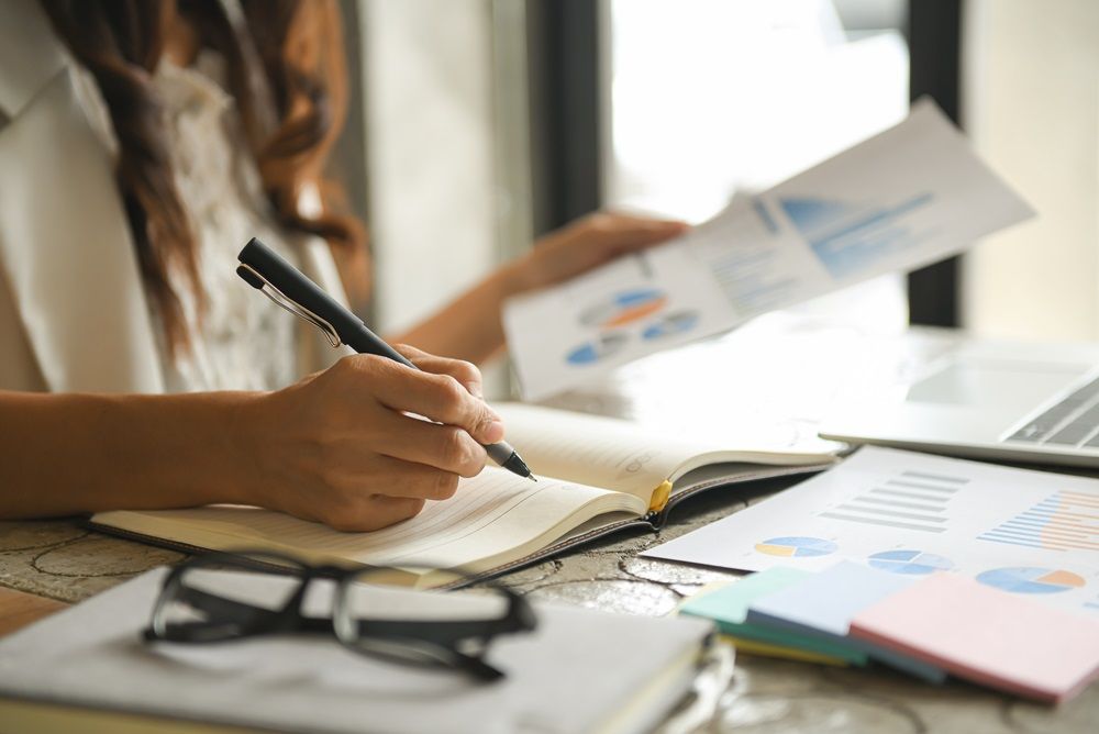 A woman is sitting at a desk writing in a notebook.