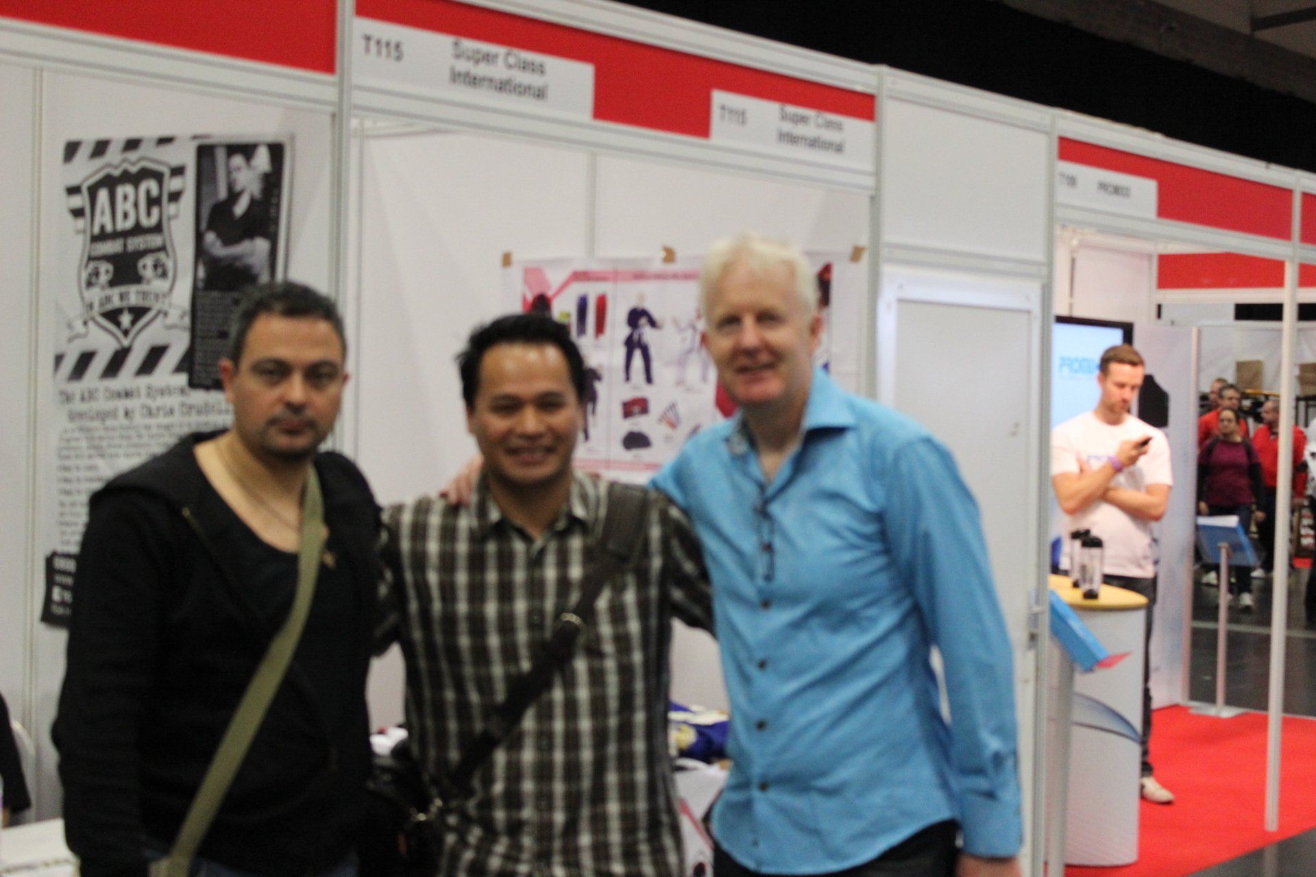 Three men pose for a picture in front of a sign that says abc