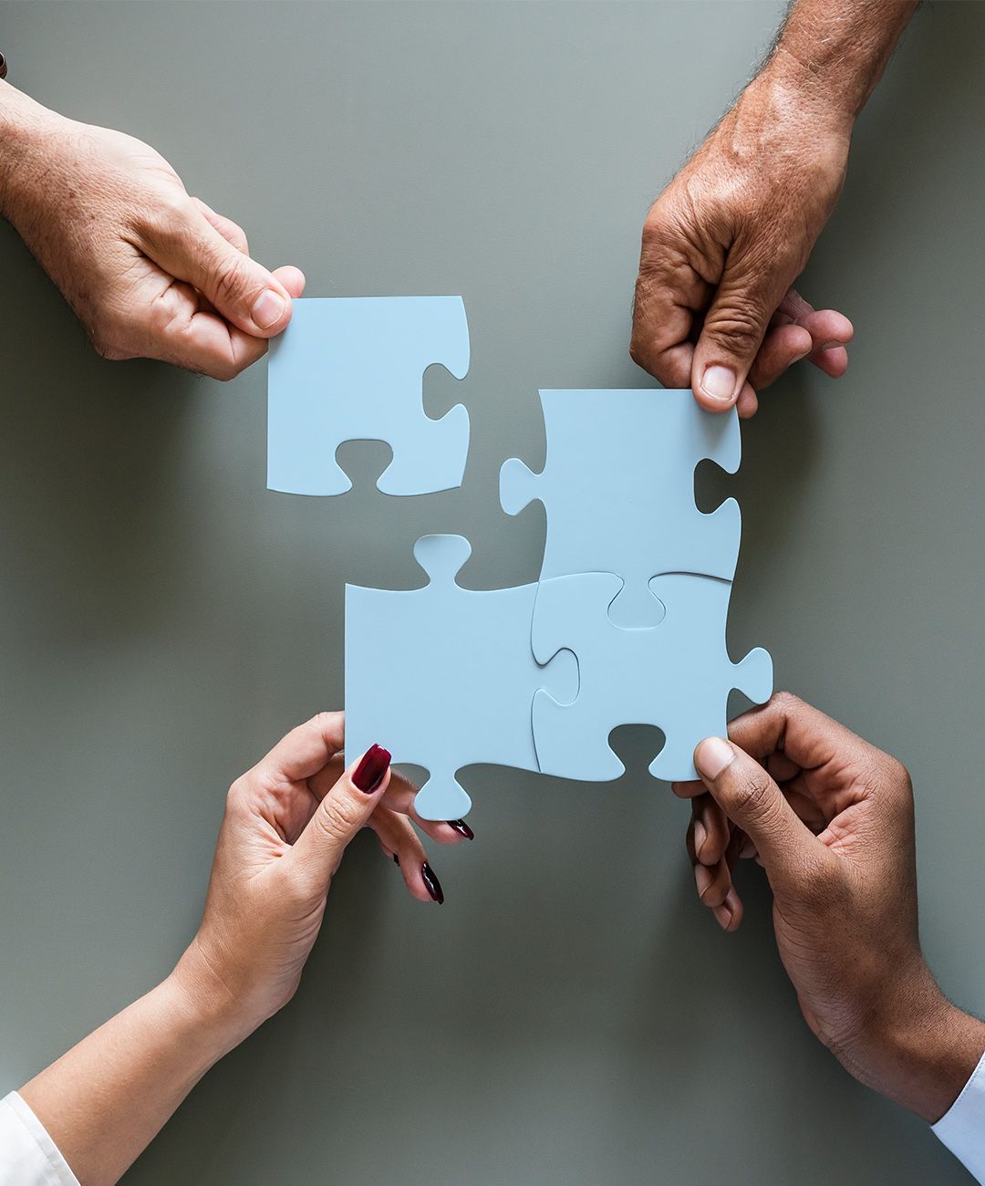 A group of people are holding blue puzzle pieces in their hands.