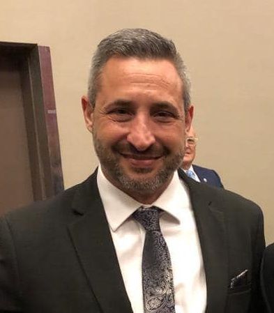 A man in a suit and tie is smiling for the camera.