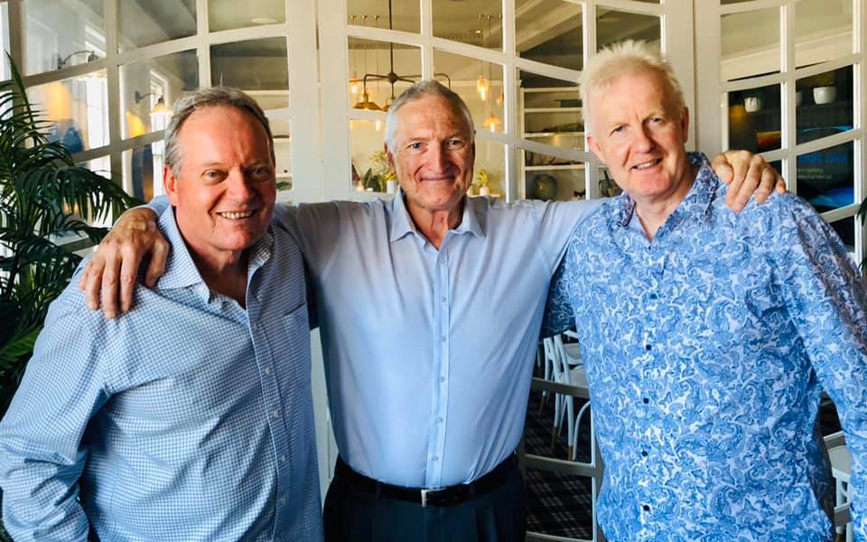 Three men are posing for a picture together in a room.