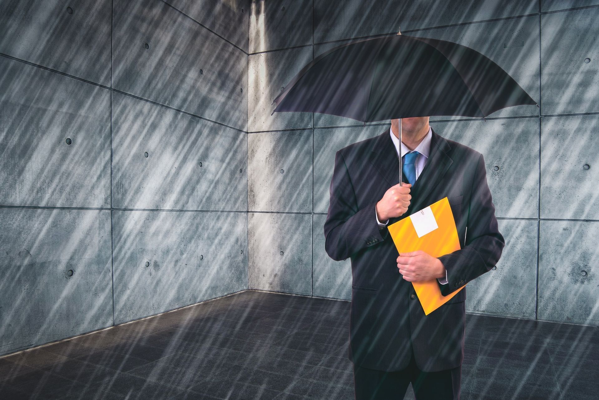 Man in suit holding umbrella, folder in rain, inside a concrete room.