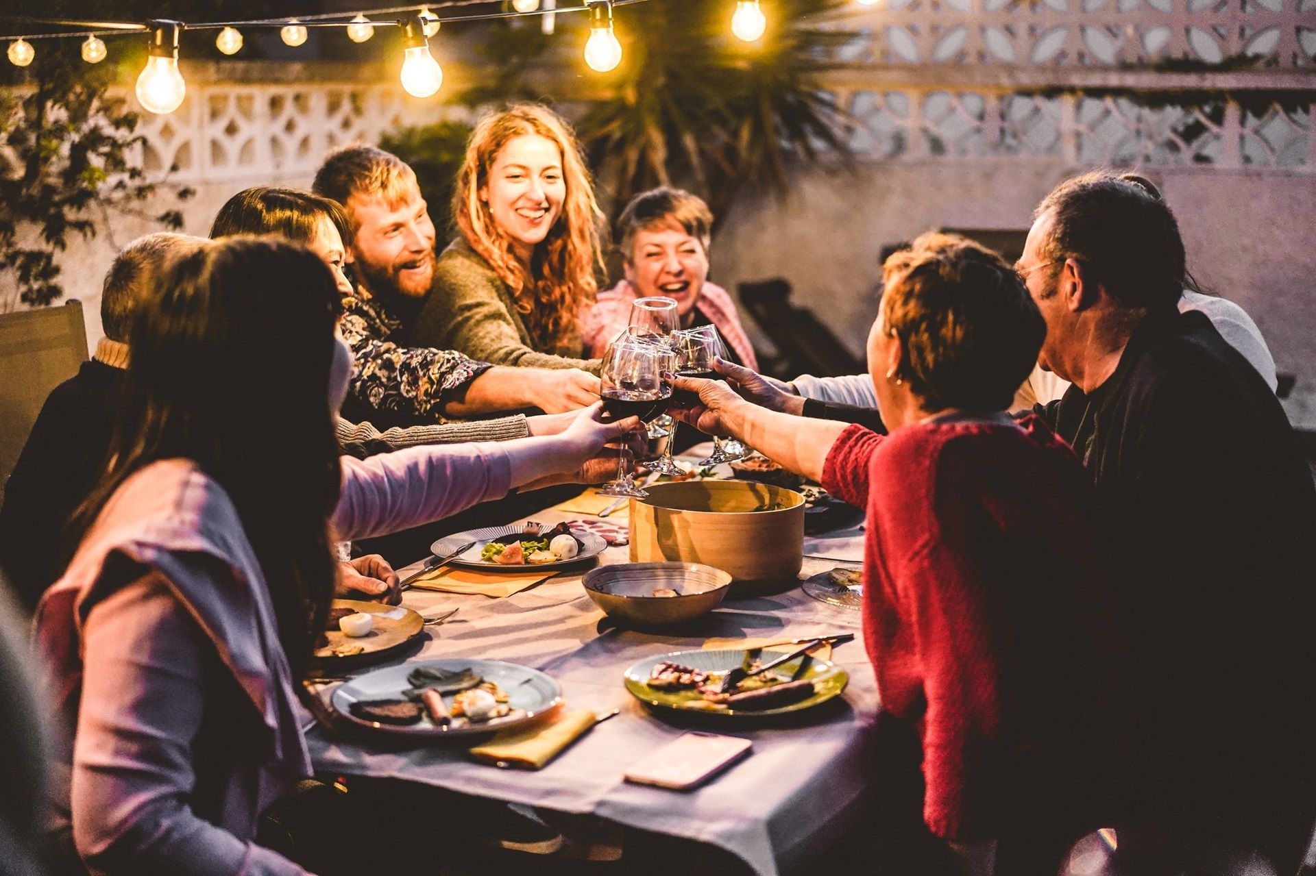 A group of people are sitting around a table eating food and drinking wine.