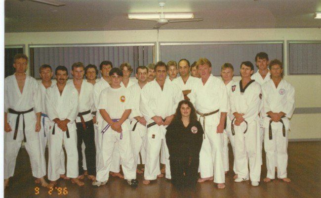 A group of people in white karate uniforms pose for a photo