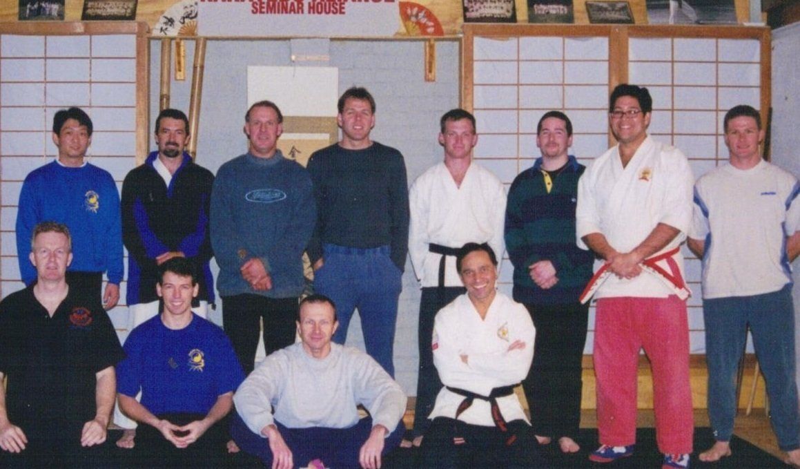 A group of men are posing for a picture in front of a sign that says karate