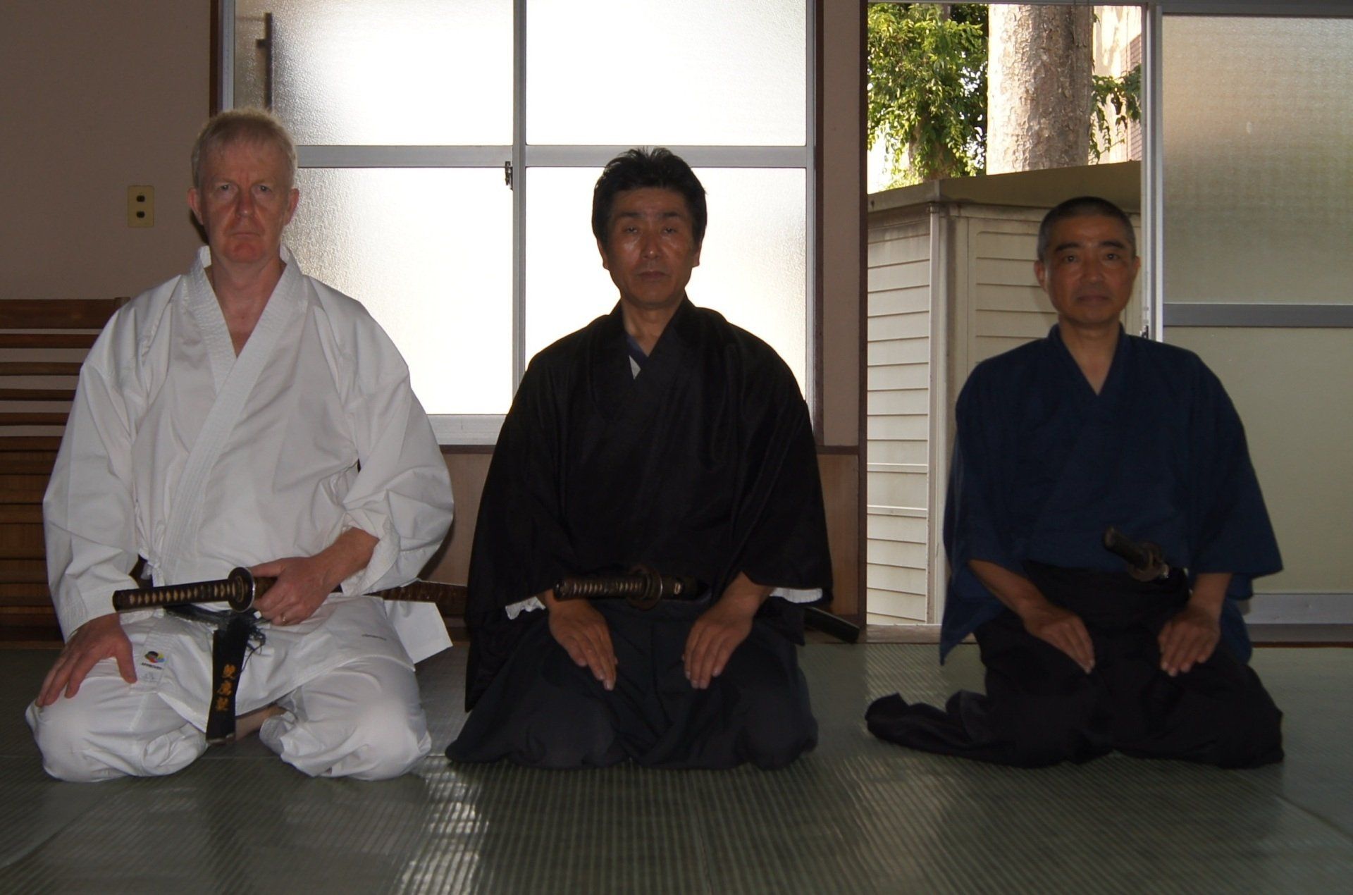 Three men are sitting on the floor holding swords