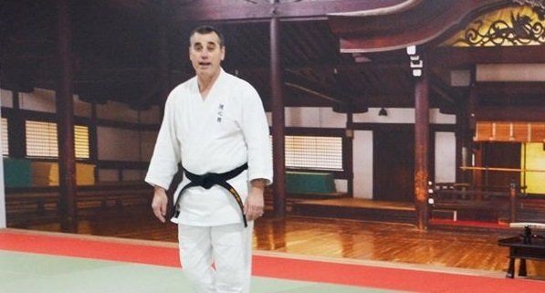 A man in a white karate uniform with a black belt