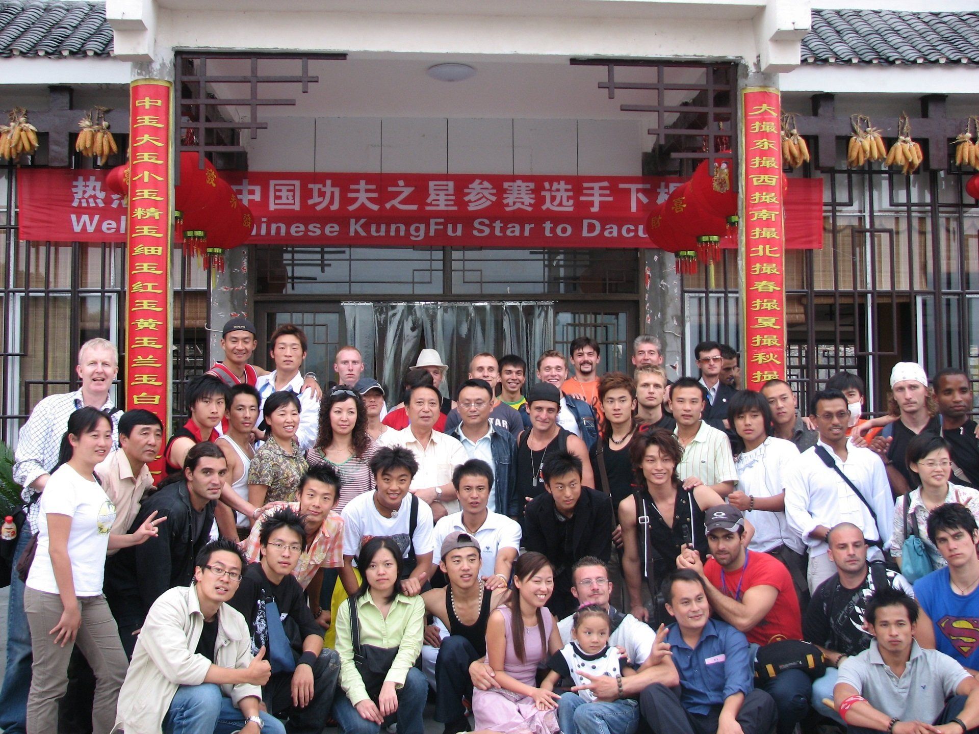A group of people posing for a picture in front of a sign that says chinese kung fu star to duel