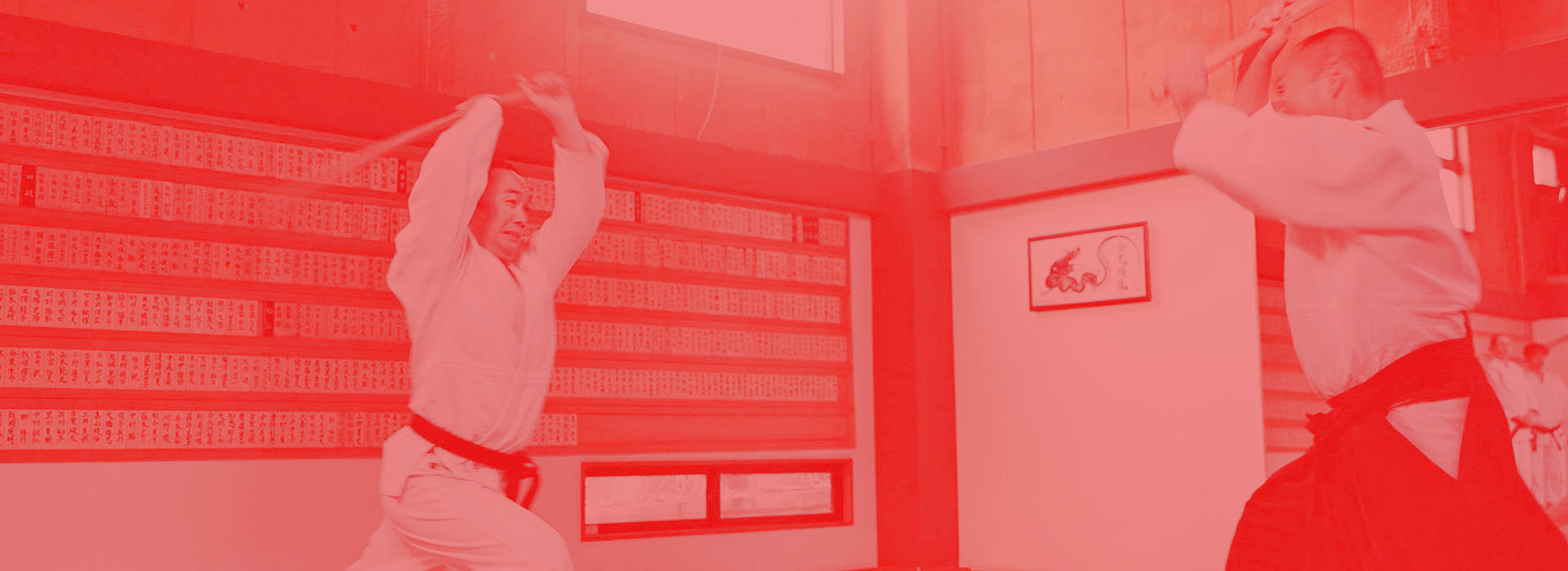 A couple of people are practicing karate in a gym.