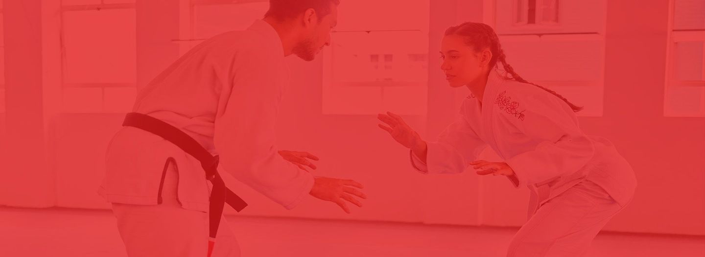 A man and a woman are practicing martial arts in a gym.
