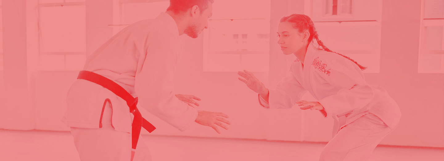 A man and a woman are practicing martial arts in a gym.