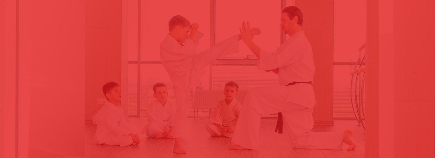A group of young men are practicing karate in a gym.