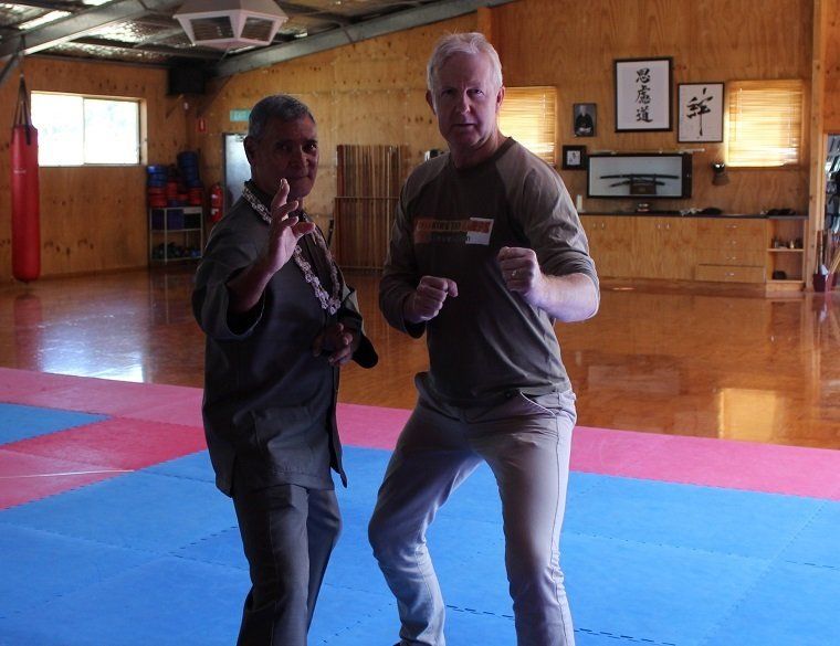 Two men are standing on a mat in a gym