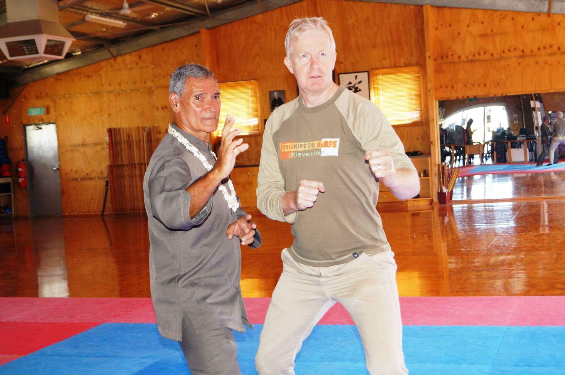 A man wearing a shirt that says ' karate ' on it is standing next to another man