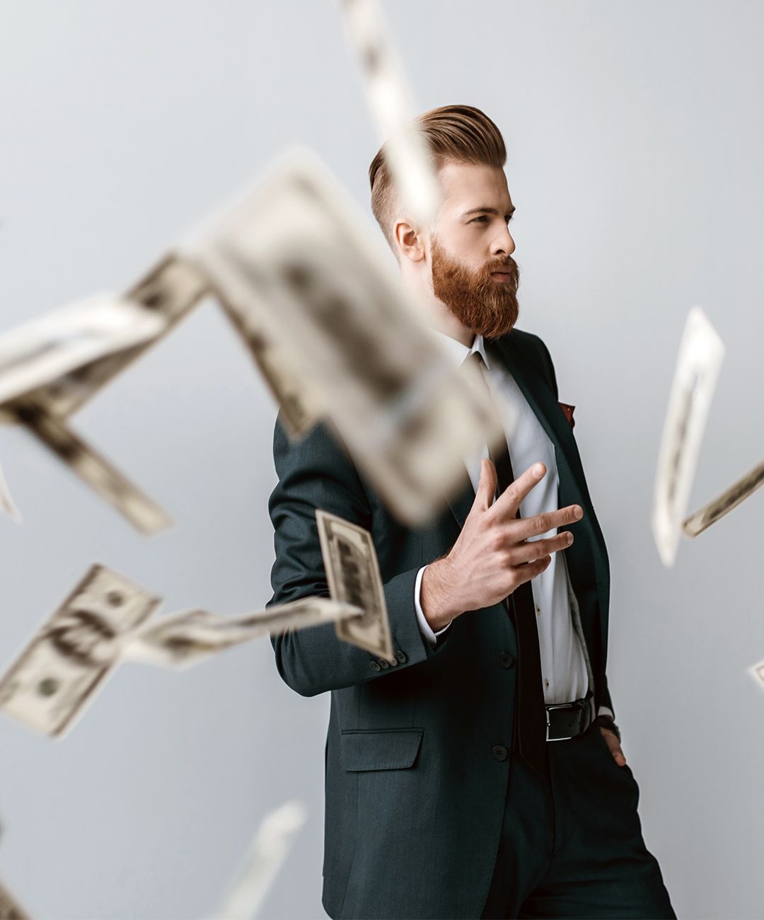 A man in a suit and tie is surrounded by money falling from the sky.