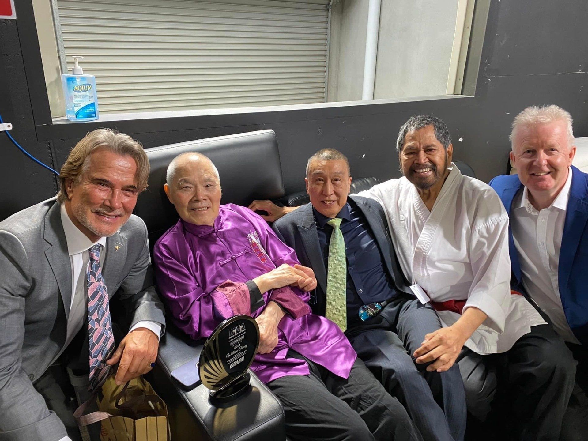 A group of men are posing for a picture while sitting on a couch.