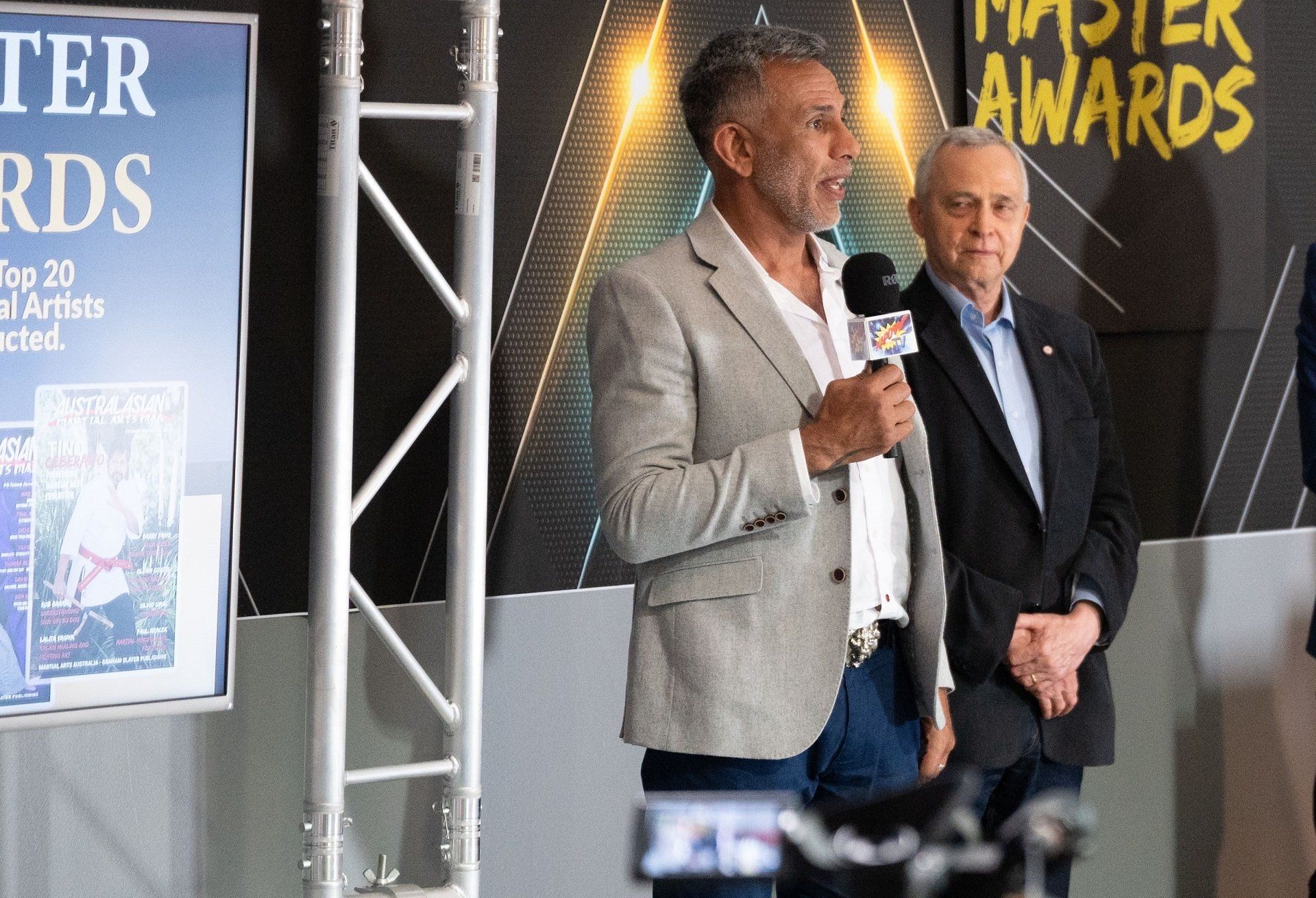 Two men are standing in front of a sign that says master awards