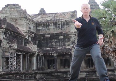 A man in a black shirt is standing in front of an old building