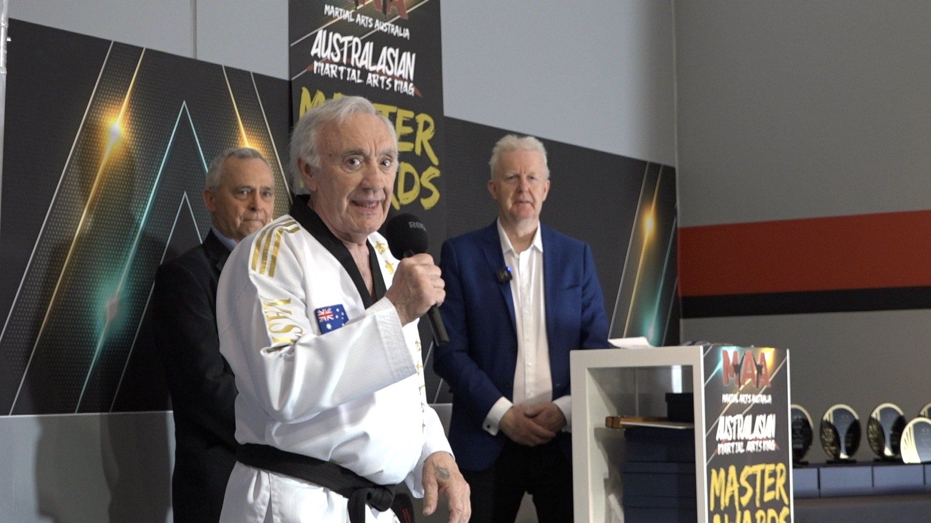 A man in a karate uniform is standing in front of a microphone.