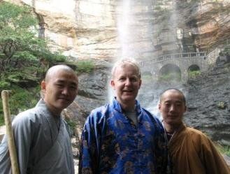 Three men are posing for a picture in front of a waterfall.