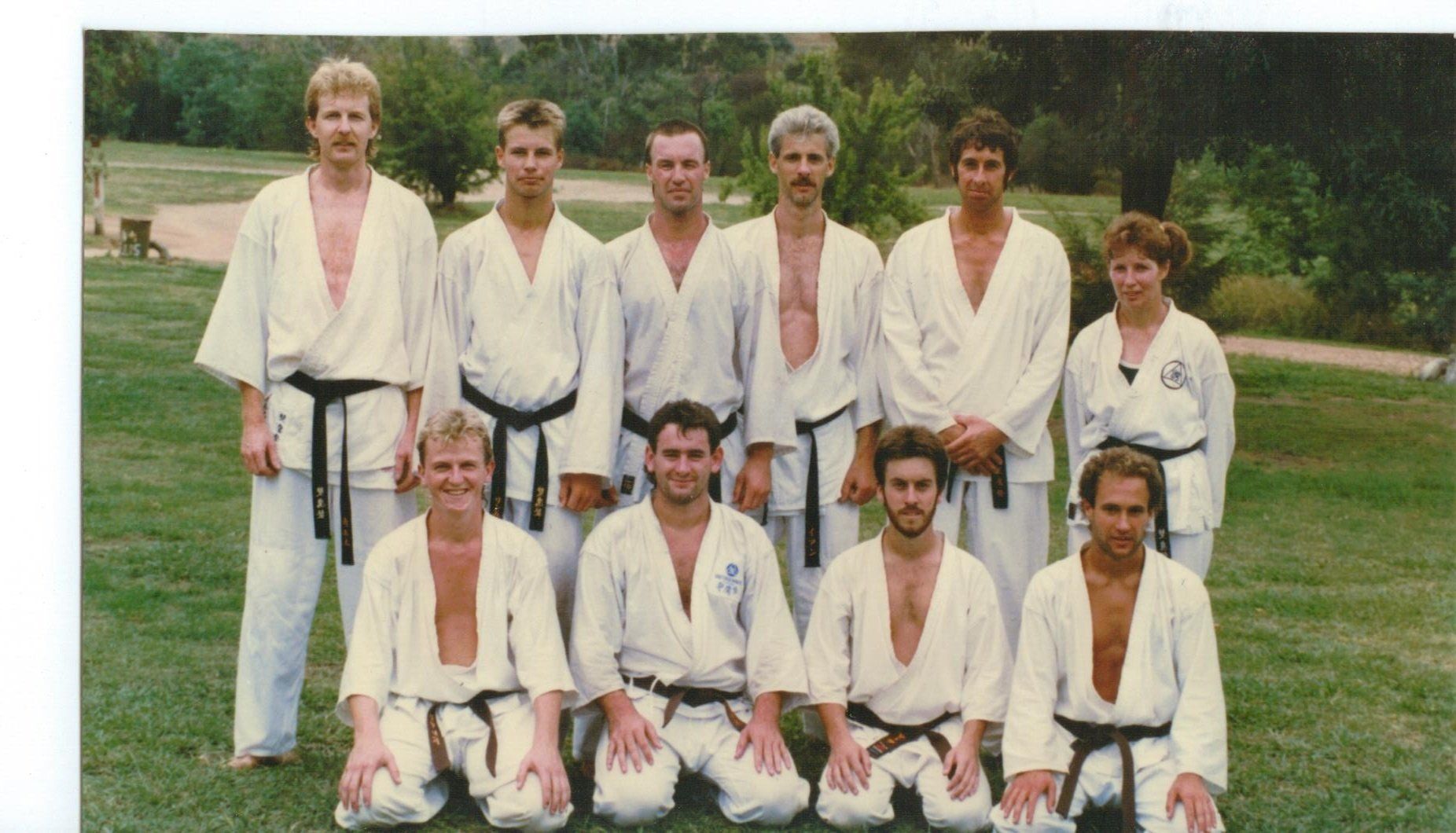 A group of men in white karate uniforms are posing for a picture