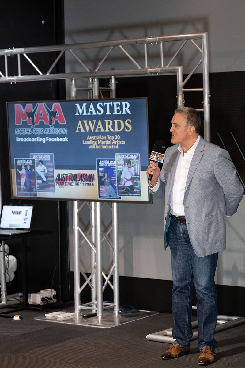 A man is standing in front of a screen that says master awards