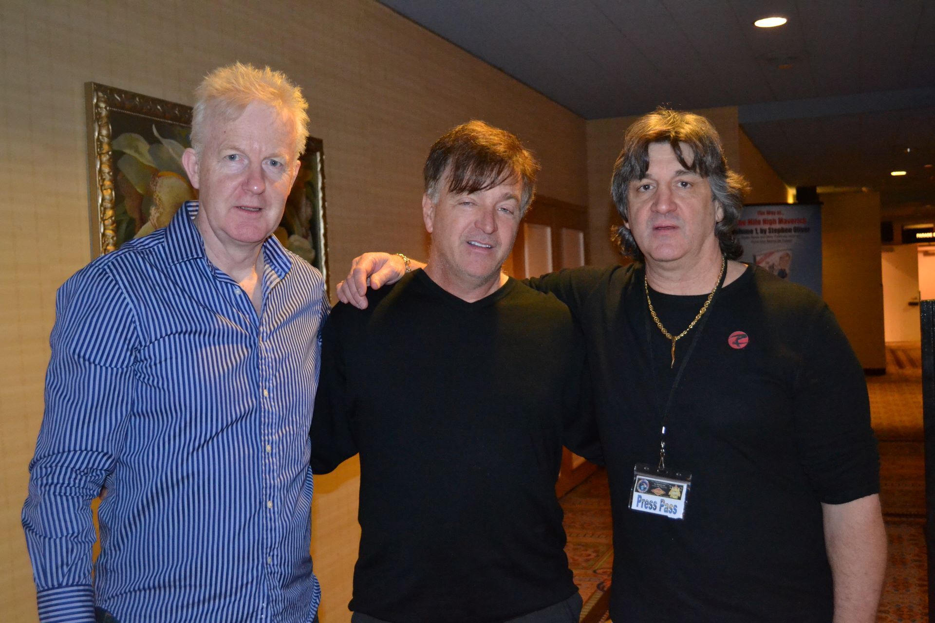 Three men are posing for a picture in a hallway