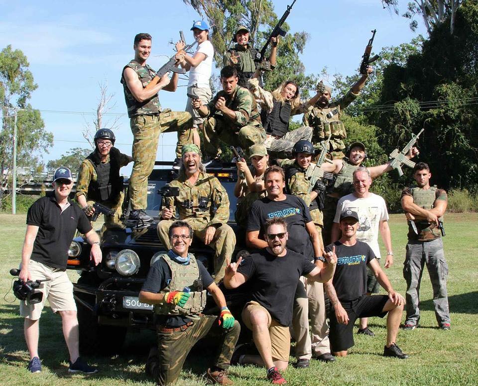 A group of soldiers are posing for a picture in front of a car.