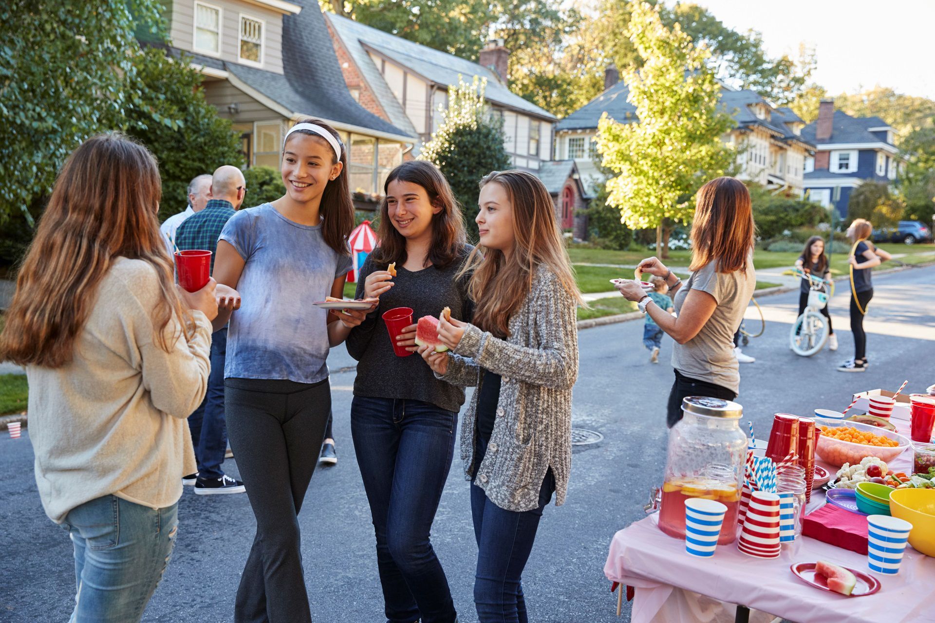 A group of young women are standing around a table in a driveway.