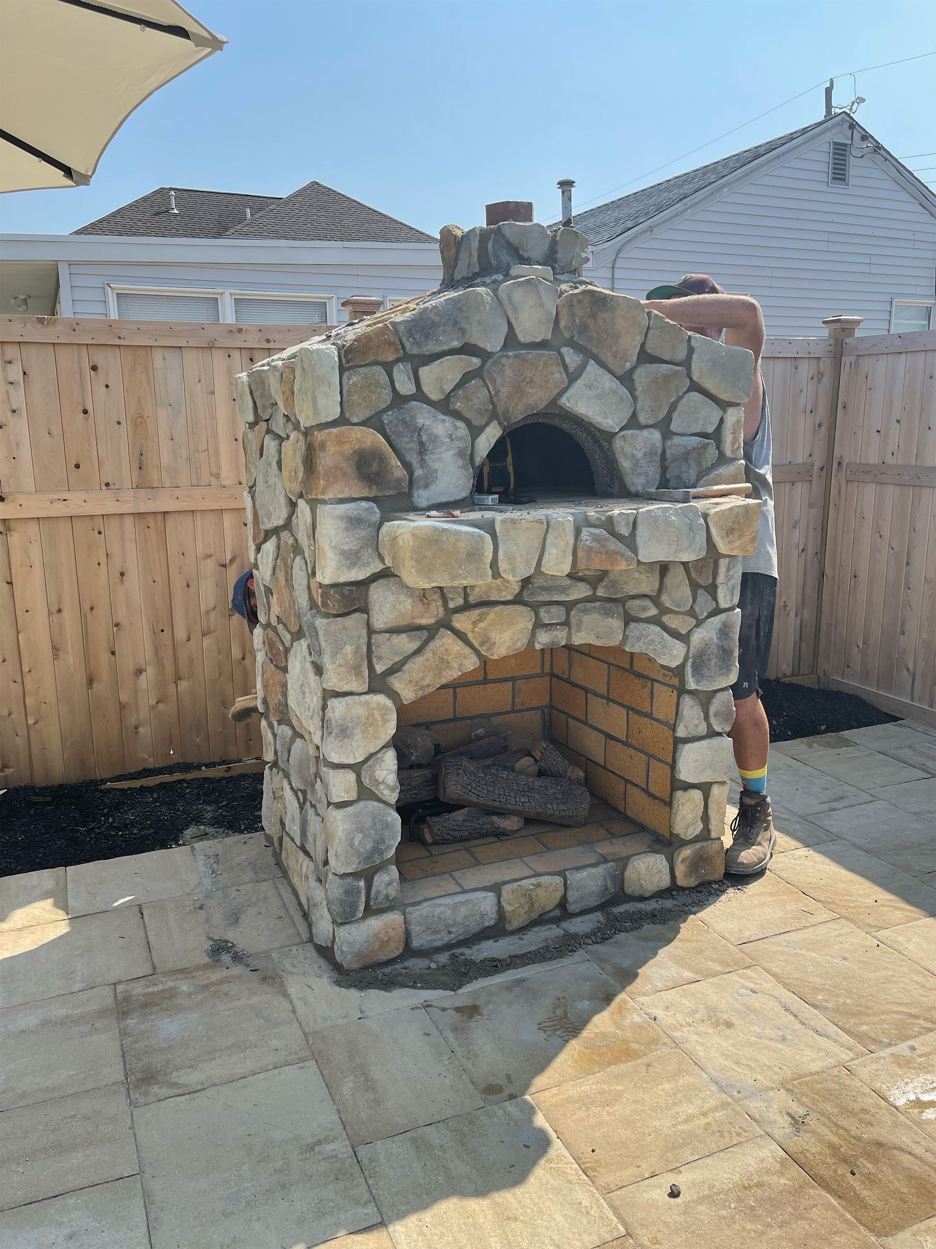 A stone fireplace with a wooden fence in the background