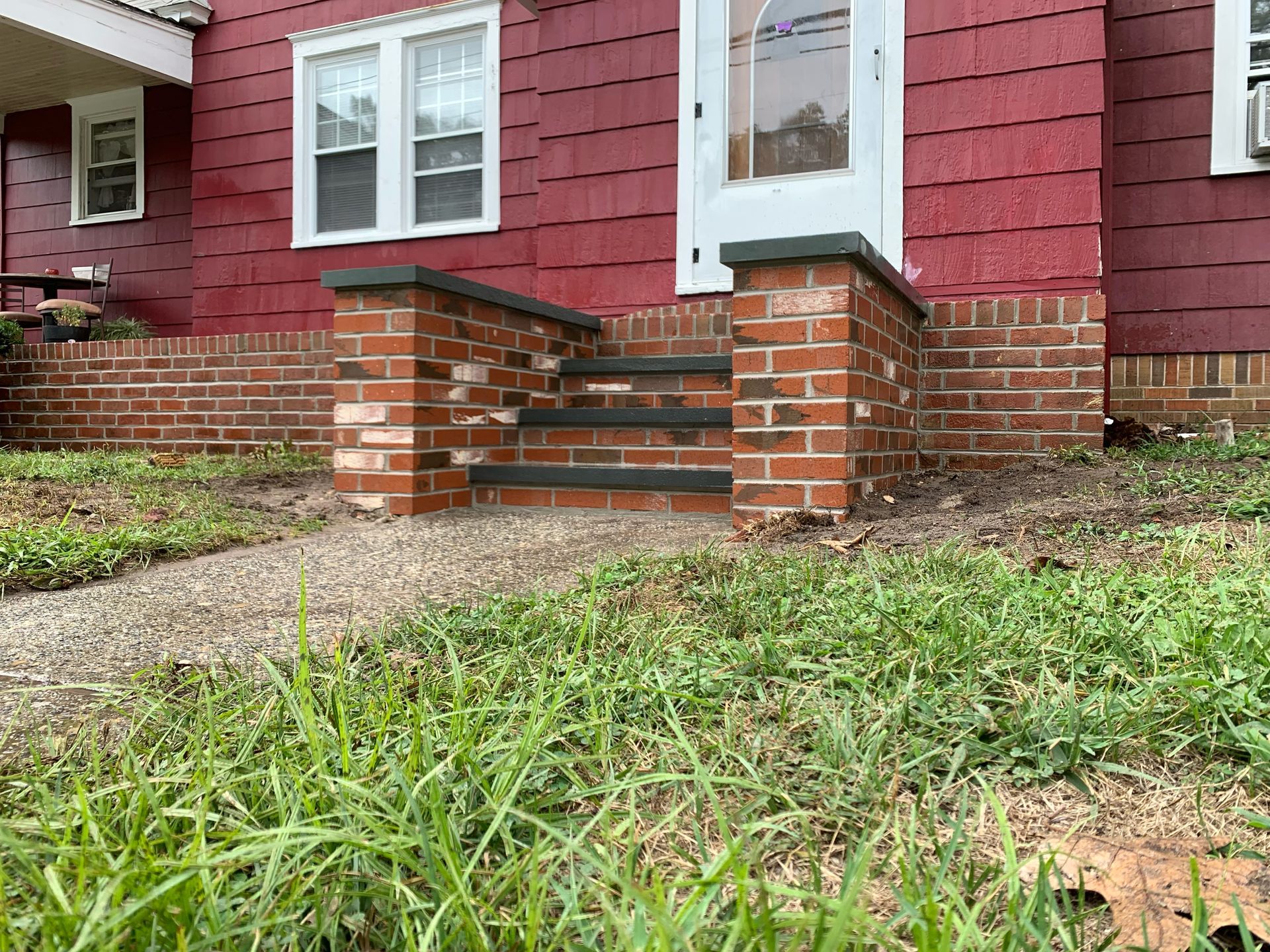 A red house with brick steps leading up to the front door.