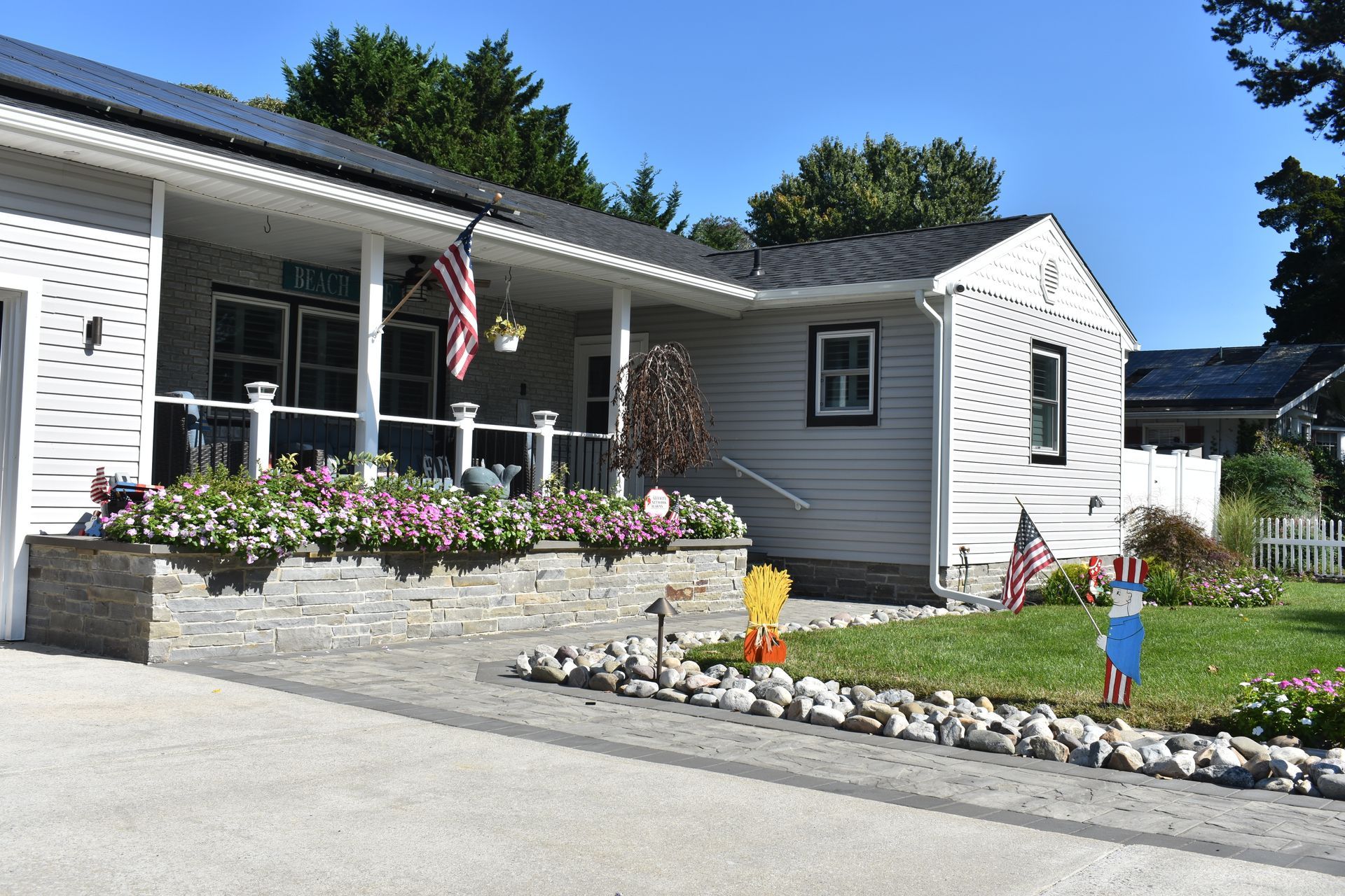 A white house with a porch and flowers in front of it