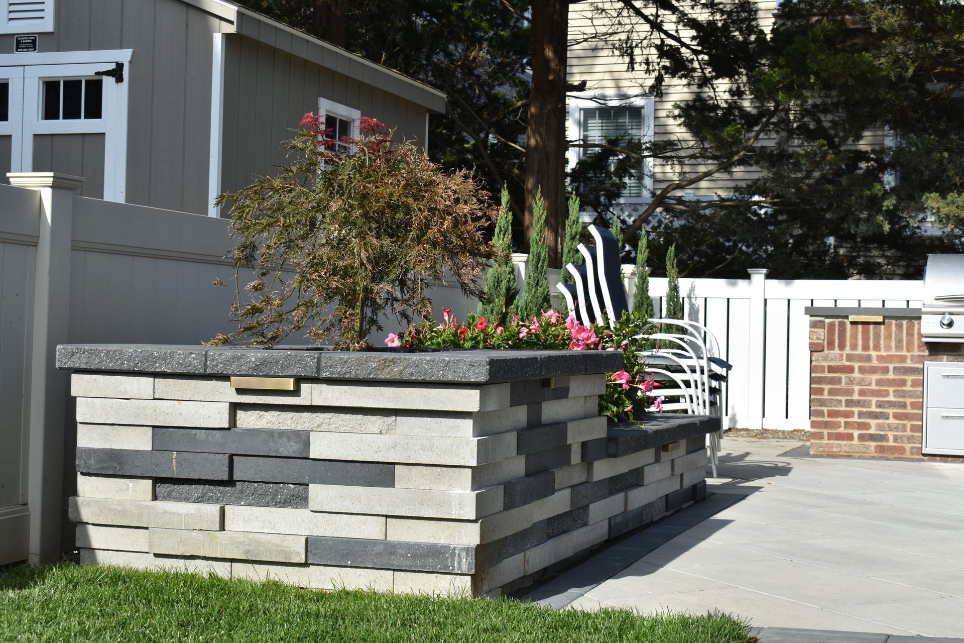 A stone wall with flowers and a grill in the background