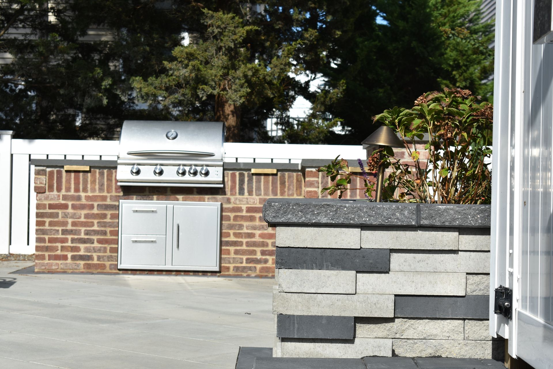 A grill is built into a brick wall next to a stone wall