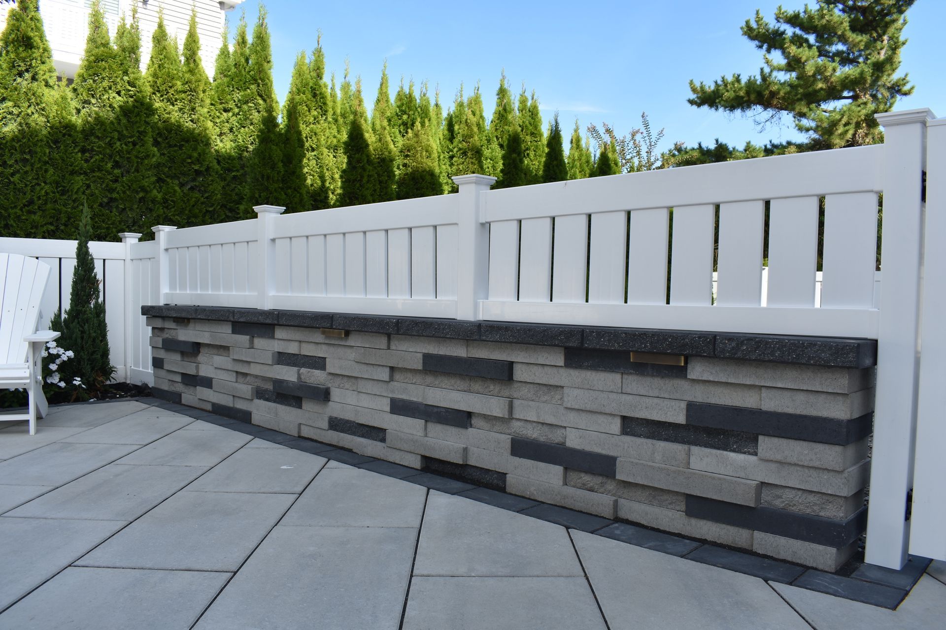 A white fence with a stone wall behind it