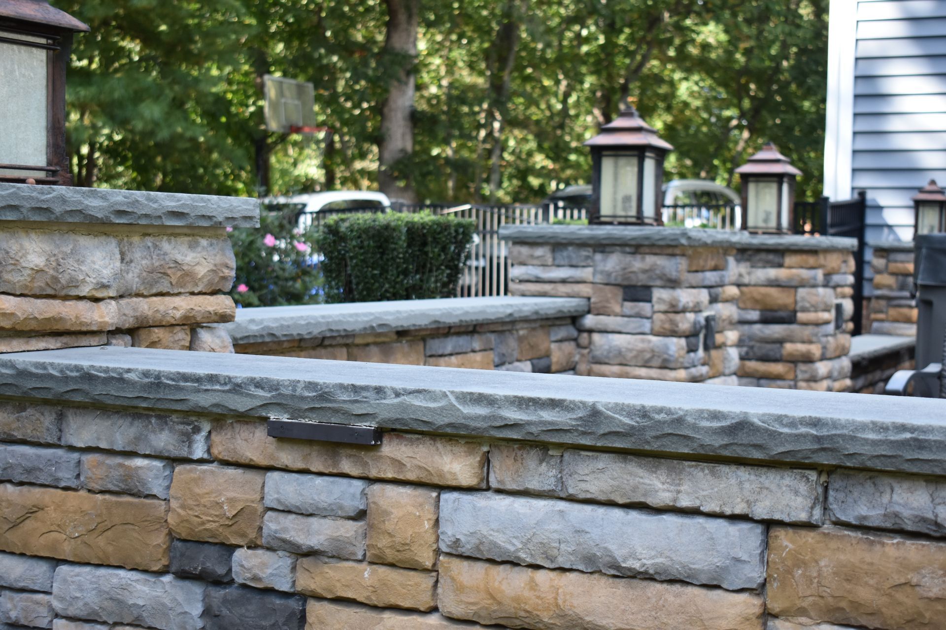 A stone wall with lanterns on top of it in front of a house.