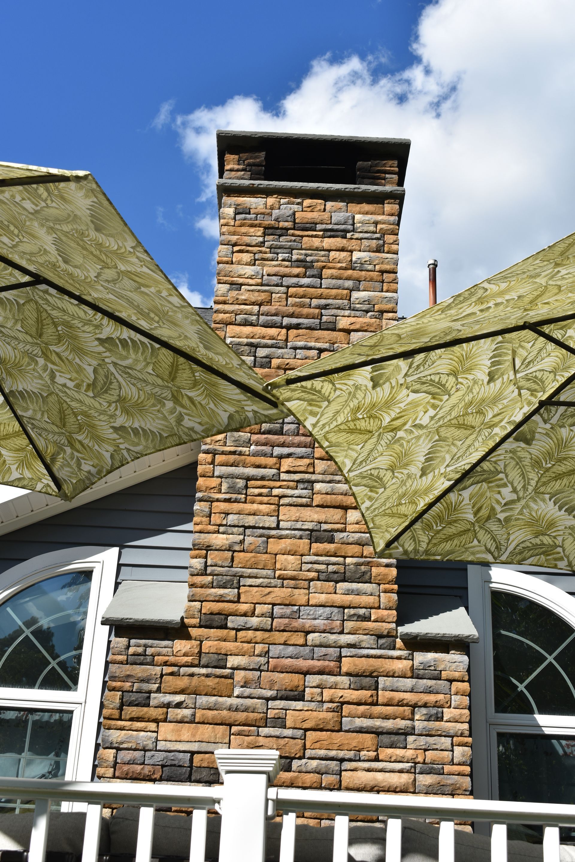 A brick chimney with two umbrellas in front of it