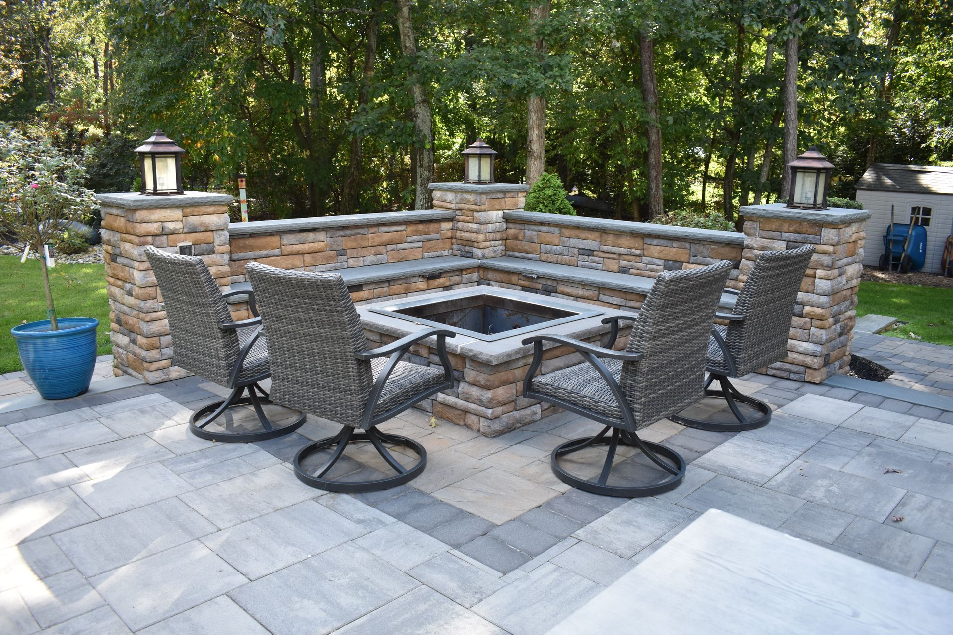 There is a fire pit in the middle of the patio with chairs around it.